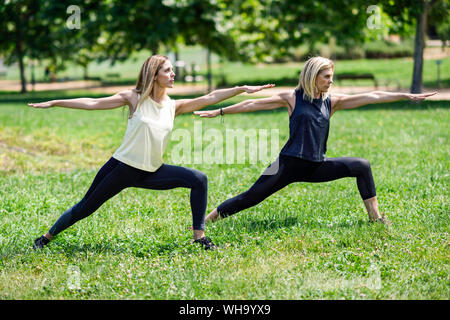 Young woman doing yoga avec sa fille dans un parc Banque D'Images