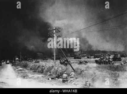WW2 : l'avance par l'Armée canadienne avec les troupes britanniques vers Falaise, France. Photo montre les incendies causés par les bombardements avec transport et les hommes se mettre à couvert sur la route Caen-Falaise. 11 août 1944. Banque D'Images