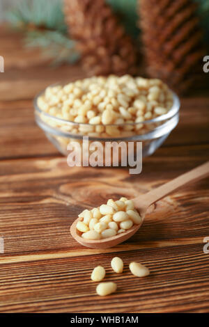 Noix de pin, cèdre dans bol en verre avec les cônes de cèdre, spoon brunch sur fond de bois. Banque D'Images