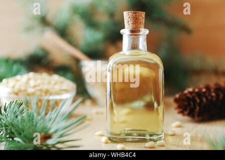 Produits cèdre : Cèdre de l'huile dans la bouteille en verre, les noix de pin, cônes, des brunchs sur un fond en bois broun Banque D'Images