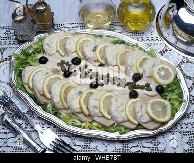 La nourriture bien présentée sur un plateau d'argent - la viande, les rondelles de citron, les câpres, les olives, la sauce et de laitue - longe de porc ou jambon peut-être ?. Banque D'Images