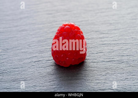 Vue rapprochée d'une framboise sur une plaque tableau noir Banque D'Images