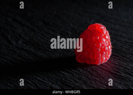 Vue rapprochée d'une framboise sur une plaque tableau noir Banque D'Images