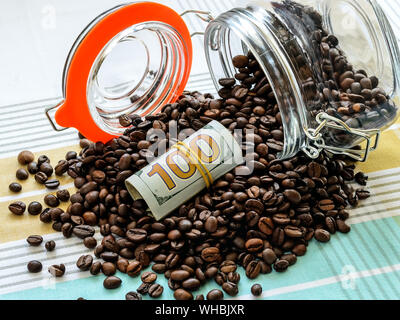 Rouleau de cent billets d'un dollar et les grains de café se dispersa d'tombé bocal en verre sur une nappe. Pour les produits alimentaires en vrac peut comme cache ou coffre-fort. Banque D'Images