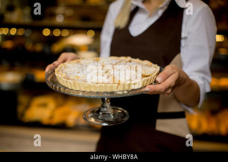 Portrait of female bakery worker posing avec apple tart dans Baker shop Banque D'Images