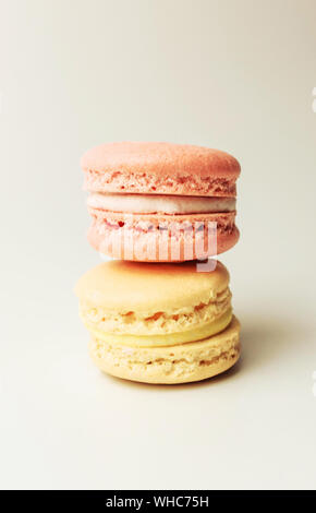 Stand macarons jaune et rose sur le dessus de l'autre sur un fond blanc, isoler Banque D'Images