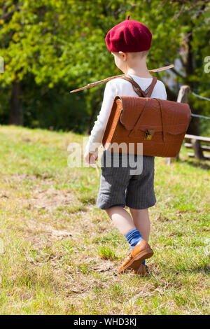Mignon petit écolier primaire vu de retour à pied piscine chemin de l'école dans des vêtements et nostalgique (satchel copie espace) Banque D'Images