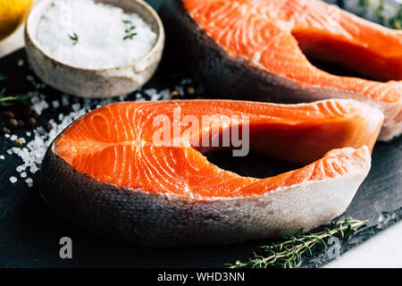 Darnes de saumon cru sur fond d'ardoise noire, vue rapprochée. Prête pour la cuisson du poisson cru Banque D'Images
