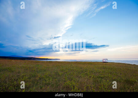 Un solitaire van contre un coucher de soleil spectaculaire avec la campagne et à la mer Banque D'Images