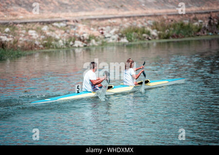 Équipe d'un jeune homme et femme sur l'athlète rowing kayak sur le lac pendant la compétition. Accent sur l'eau Banque D'Images