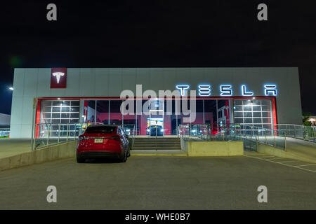 La concession et le hall d'exposition Tesla avec le modèle X de Tesla stationnés en dehors de l'avant la nuit. Banque D'Images