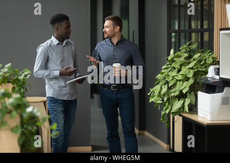 Friendly divers partenaires masculins parler marcher dans office hallway Banque D'Images