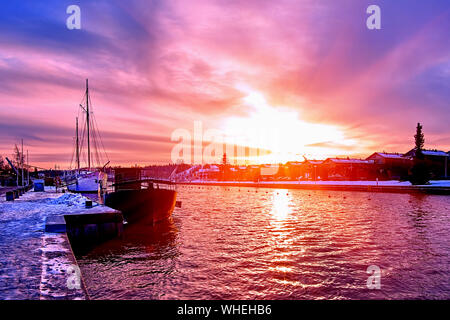 Scenic rouge violet et violet coucher de soleil sur la rivière campagne en Europe avec de vieux navires ayant reste à l'harfang harbour pier Banque D'Images