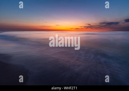 Ciel coloré sur la mer du Nord après le coucher du soleil sur la plage de Juist, îles de la Frise orientale, en Allemagne. Banque D'Images