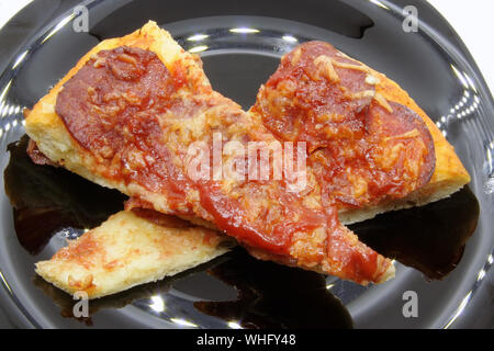 Coupe pizza sur une plaque noire. Pizza slice sur une plaque noire. Banque D'Images