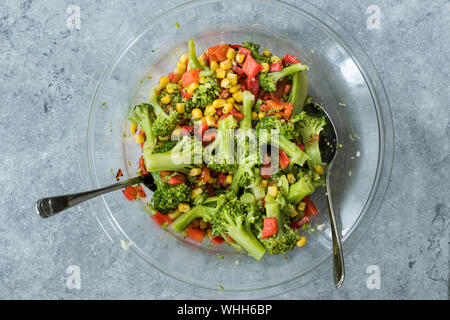 Salade de brocoli avec le poivron rouge et le maïs au bol en verre. L'alimentation biologique. Banque D'Images