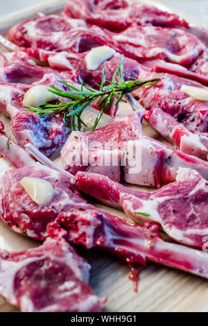 Côtelettes d'agneau cru mariné à l'ail et du romarin frais. La nourriture de la viande biologique. Banque D'Images