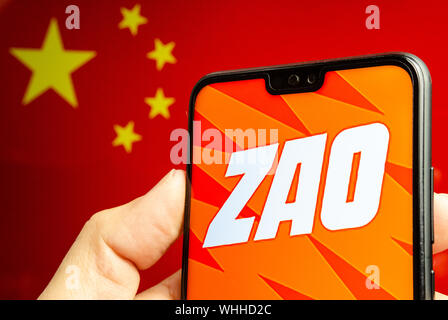 Côté est titulaire d'un smartphone avec ZAO app logo. Le drapeau de la Chine au flou l'arrière-plan. Zao est actuellement un certain nombre d'hôtesse d'une app en Chine. Banque D'Images