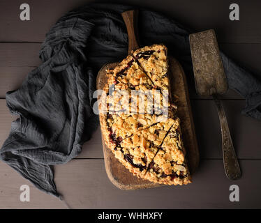 La moitié crumble Tarte aux prunes sur une planche à découper en bois brun, vue du dessus Banque D'Images