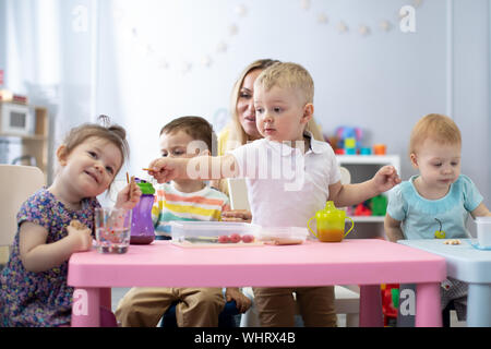 Les enfants ont un dîner à l'école maternelle. Peu de tout-petits garçons et filles de ce groupe d'enfants assis à la table avec déjeuner et manger appétissants. Chil Banque D'Images
