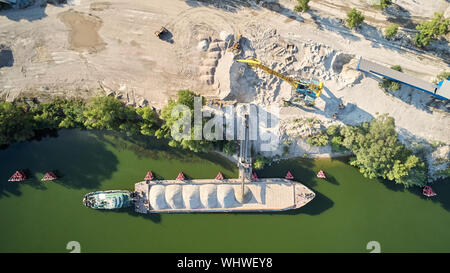 Grue de chargement est sable et gravier dans une barge Bateau pour le transport fluvial. Drone aérien Banque D'Images
