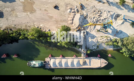 Grue de chargement est sable et gravier dans une barge Bateau pour le transport fluvial. Drone aérien Banque D'Images