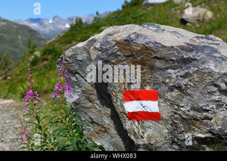 Sentier de randonnée alpine en Autriche, marqué d'un drapeau autrichien peint sur la roche solide le long de la route. Banque D'Images