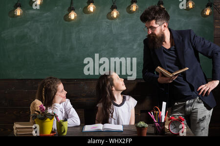 Homme à barbe des écolières, enseigne la lecture de livre. Gai Écoute curieux enfants enseignant avec attention. Enseignant et élèves filles en classe, c Banque D'Images