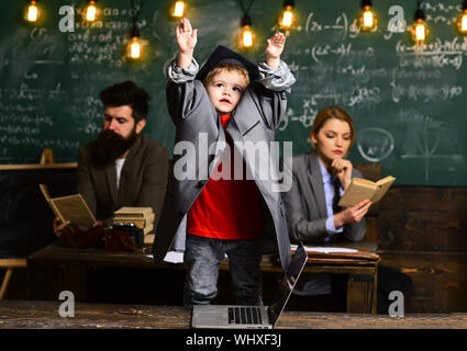 Élèves avec troubles de la mère et du père au tableau, la famille. Élève garçon en costume grand manteau et graduation cap. Banque D'Images