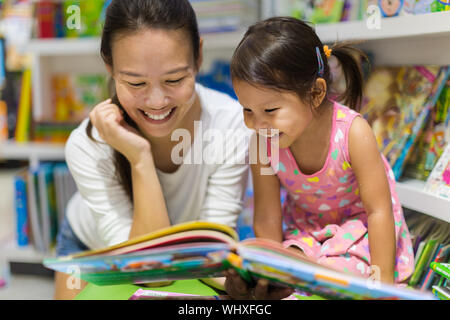 Le parent et l'enfant la lecture de livres dans la bibliothèque. Banque D'Images