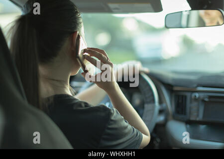 Une femme dangereuse pilote à l'aide de son portable et pas sur la route. Banque D'Images