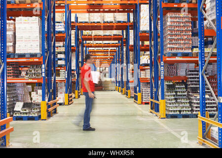 Vue latérale d'un homme marchant à travers warehouse Banque D'Images