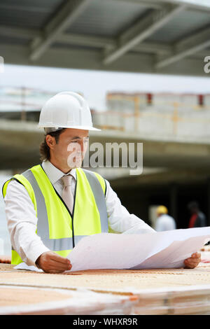 Male construction worker l'examen de plans de bâtiment sur place Banque D'Images