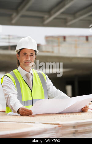 Portrait d'un homme travailleur de la construction avec le plan du site Banque D'Images