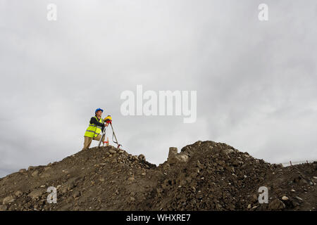 Portrait d'un arpenteur à l'aide d'un théodolite au site against sky Banque D'Images