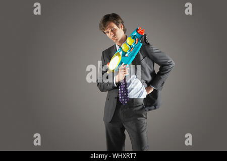 Portrait d'un homme sérieux avec de l'eau permanent contre des armes à feu arrière-plan gris Banque D'Images