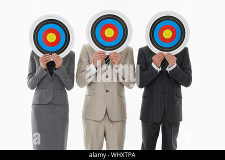 Trois cibles businesspeople holding en face de visages contre fond blanc Banque D'Images