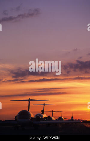 Assis sur des avions Tarmac au coucher du soleil Banque D'Images