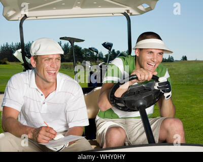 Les jeunes hommes gais de golfeurs à chariot de golf course Banque D'Images