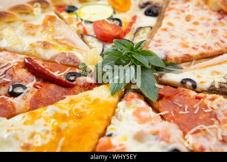 Assortiment de tranches de pizza close-up avec des ingrédients différents décoré avec du basilic, un assortiment de fast food italien traditionnel Banque D'Images