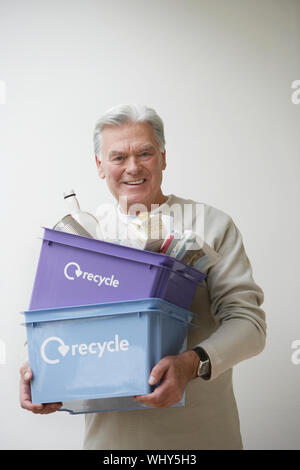 Portrait of a young man carrying bac de recyclage à l'arrière-plan gris Banque D'Images