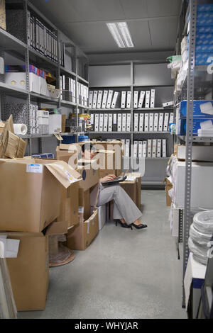 Vue latérale d'un young woman using laptop entre les boîtes de rangement Banque D'Images