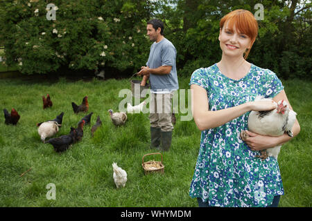 Young smiling couple poules d'alimentation sur les herbages Banque D'Images