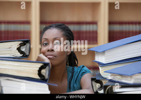 Closeup of a female office worker sitting derrière des piles de documents dans Office Banque D'Images