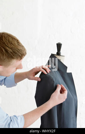 Portrait de jeune homme l'épinglage sur mesure pour convenir à manchon sur le modèle à la mode studio Banque D'Images