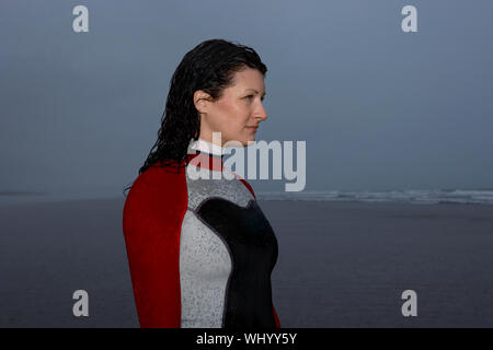 Young woman in wetsuit looking away at beach Banque D'Images