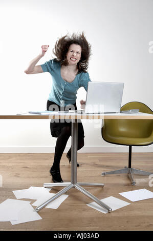 Longueur totale de angry young businesswoman hitting at desk Banque D'Images