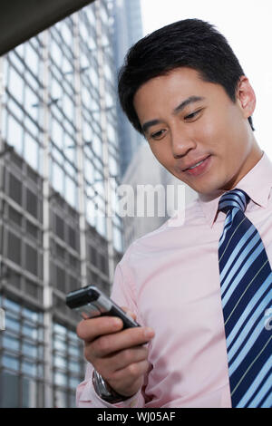 Low angle view of handsome young businessman using cell phone outside office building Banque D'Images