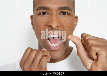 Man flossing teeth, portrait Banque D'Images