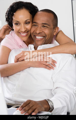Heureux couple aimant avec l'homme à l'aide d'ordinateur Banque D'Images